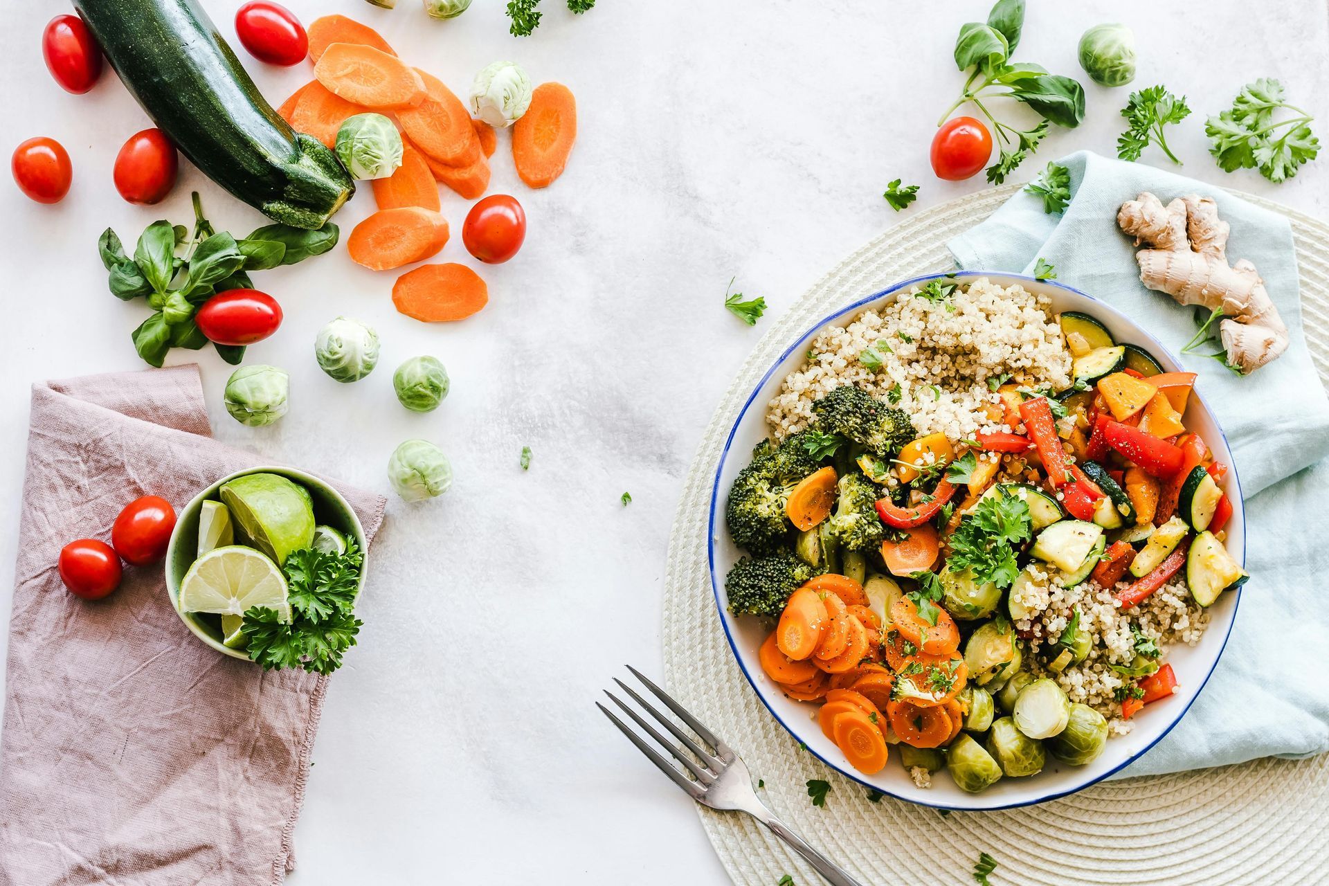 Colorful vegetable salad in a bowl with cucumber, carrots, lime, and scattered fresh produce on a light table